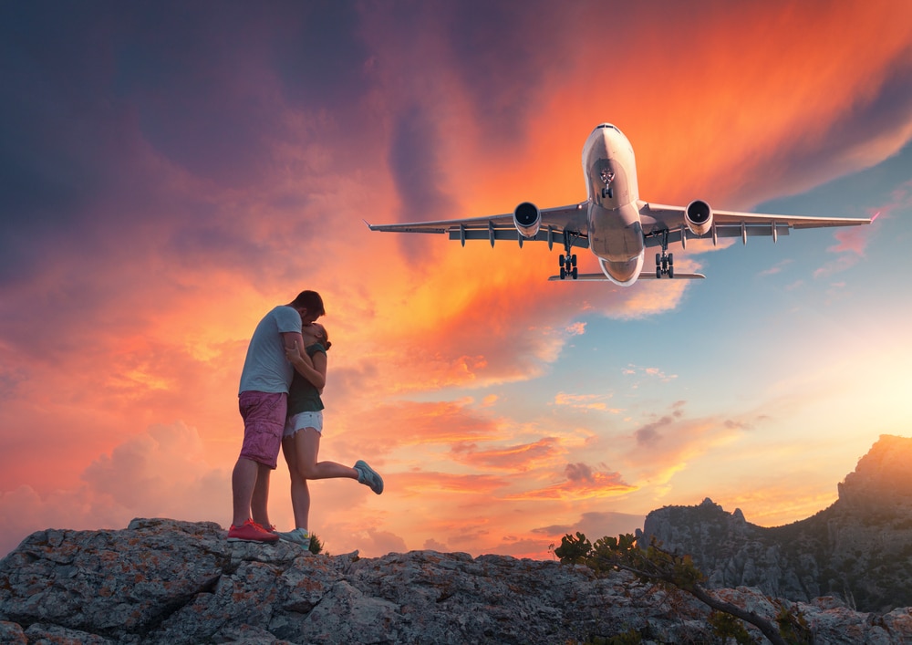 couple kissing with aircraft flying over them